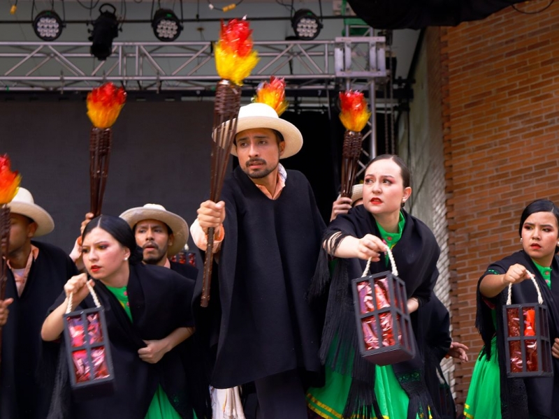 Grupo de hombres y mujeres con antorchas representando el folclor colombiano.