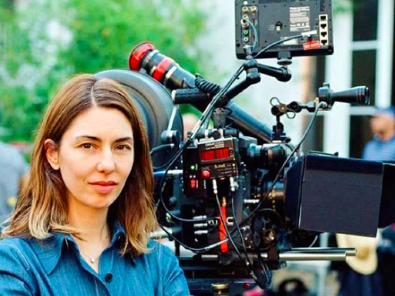 Mujer posando con cámara de cine de fondo 