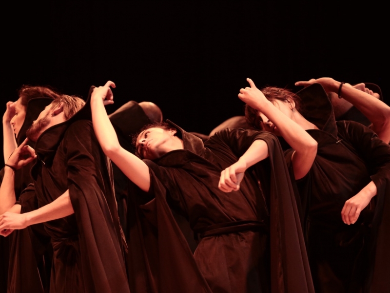 Artistas danzando vestidos de negro en escenario