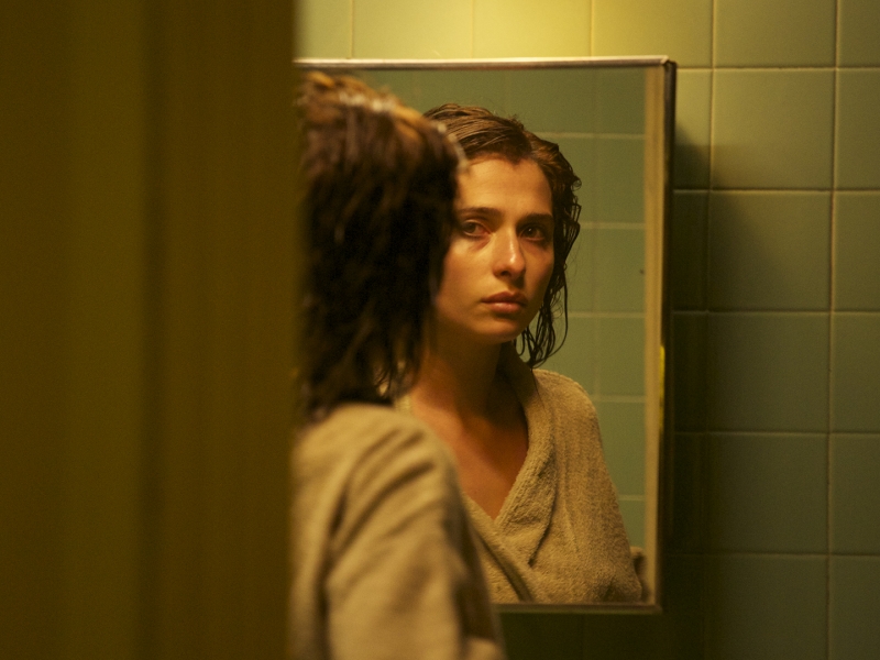 Mujer frente al espejo en un baño de luz tenue.