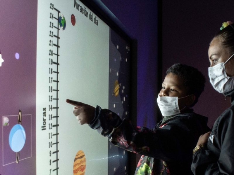 Dos personas con una pantalla táctil en el Planetario. 