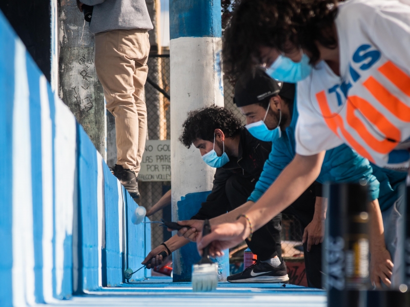 Grupo de personas pintan una zona bajo puente con rodillos