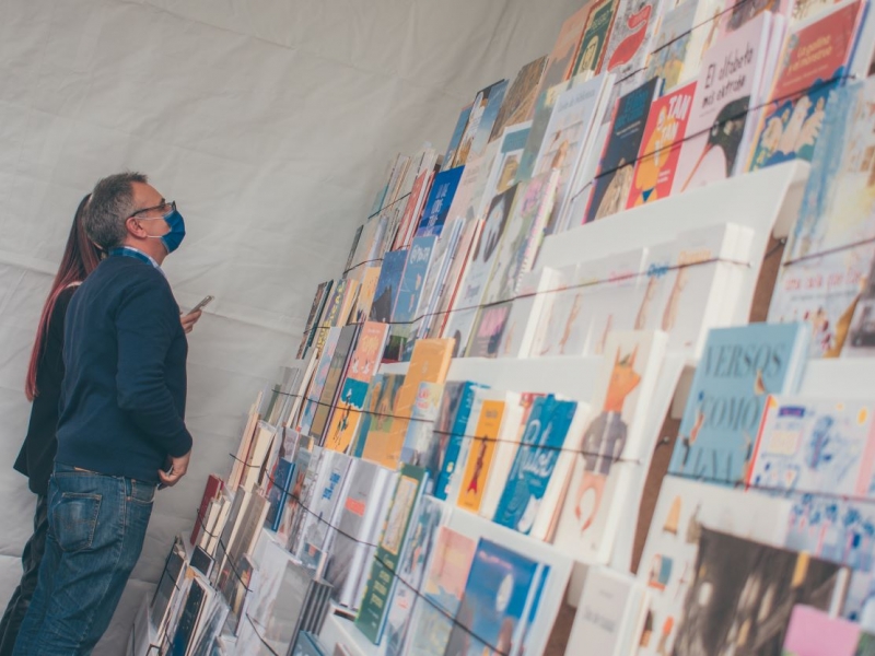 Dos personas viendo un muro con libros 