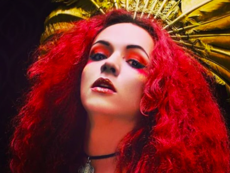 Mujer con pelo rojo y corona de pluma amarillas