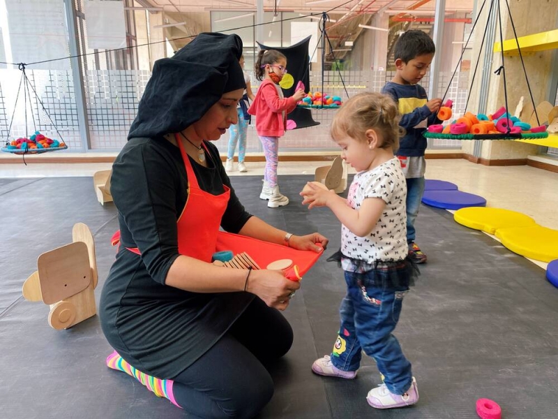 Niñas y niño con artista en laboratorio artístico