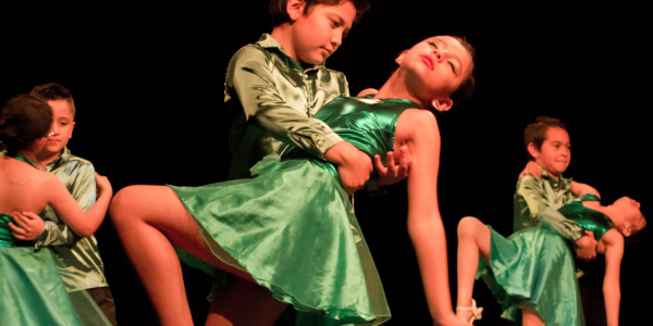 Niños bailando con trajes verdes