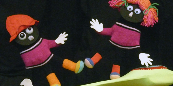 Títeres de niño y nila con saco rosa y zapatos de colores en el escenario