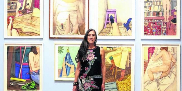 Karen Lamassonne fotografiada frente a varios de sus cuadros