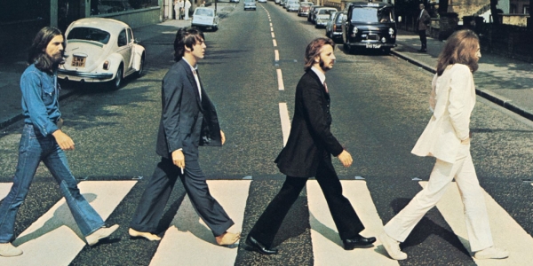 Integrantes de The Beatles caminando sobre la zebra en una calle. 