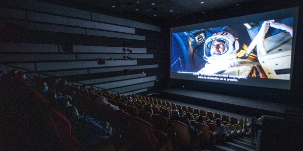 Sala oscura de Cinemateca con proyección de astronauta de fondo. 