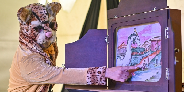 Artista con disfraz de tigre presentando pintura para niños