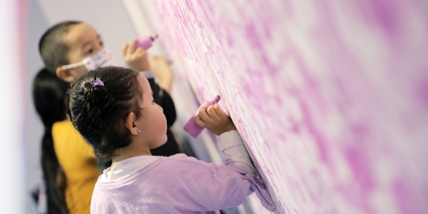 Niños escribiendo con crayola sobre una pared.