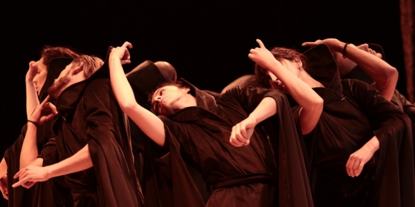 Artistas danzando vestidos de negro en escenario
