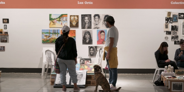 Dos personas y un perro admiran las obras en un stand de las Ferias Locales de Artes en La Candelaria