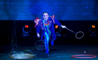 Hombre vestido con disfraz de azules con muñecos sobrepuestos haciendo burbujas.