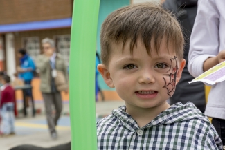 Niño con telaraña pintada en su cara, sonriendo 