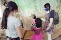 Artistas del Programa Nidos compartiendo con una niña en primera infancia durante experiencia artística.