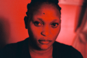 Mujer mirando de frente en un cuarto con luz roja 